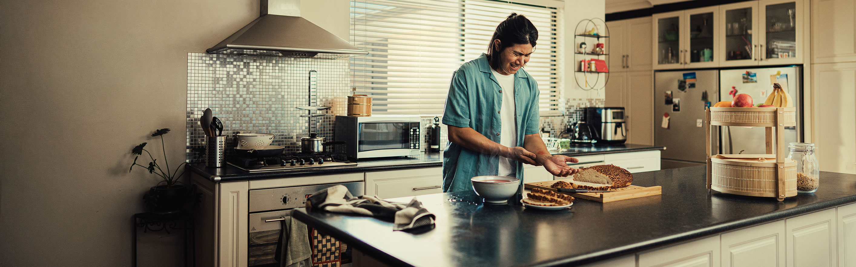 Man cooking in kitchen holding his fore arm due to a burn